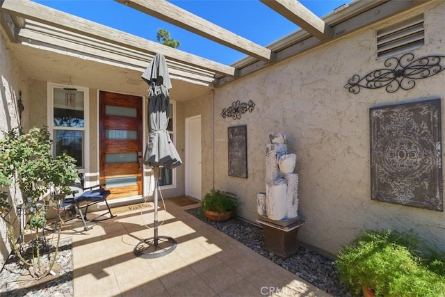 property entrance with a patio and stucco siding