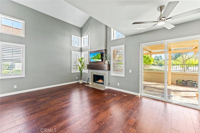 unfurnished living room with a fireplace with flush hearth, baseboards, ceiling fan, and wood finished floors