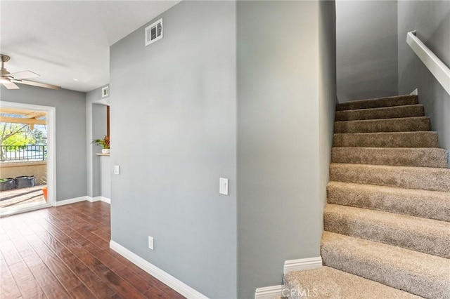 stairs with visible vents, wood finished floors, a ceiling fan, and baseboards