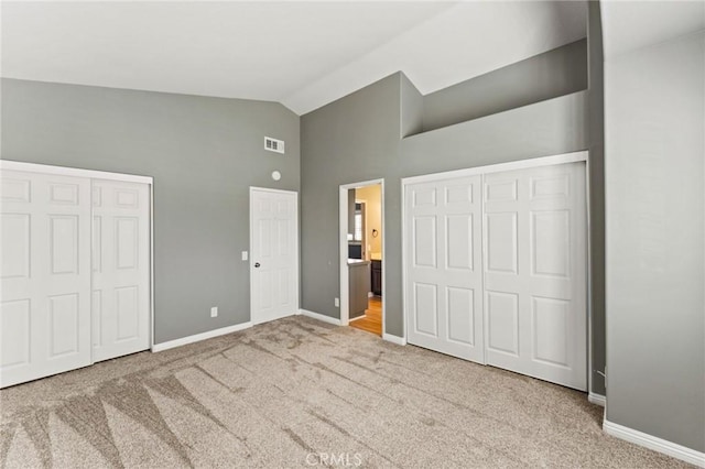 unfurnished bedroom featuring lofted ceiling, carpet, visible vents, and baseboards