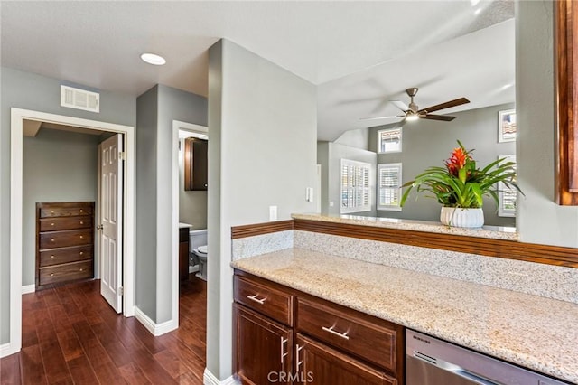 kitchen with light stone counters, dark wood-style flooring, visible vents, and dishwasher