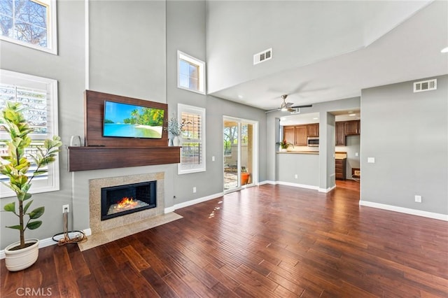 unfurnished living room featuring a premium fireplace, dark wood-style flooring, visible vents, and baseboards