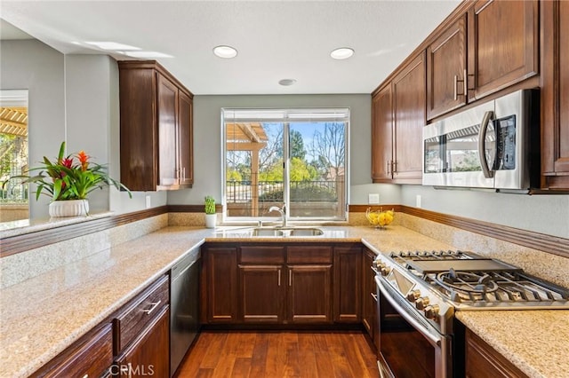 kitchen featuring dark wood-type flooring, light stone counters, stainless steel appliances, and a sink