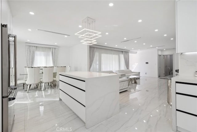 walk in closet with marble finish floor and a notable chandelier