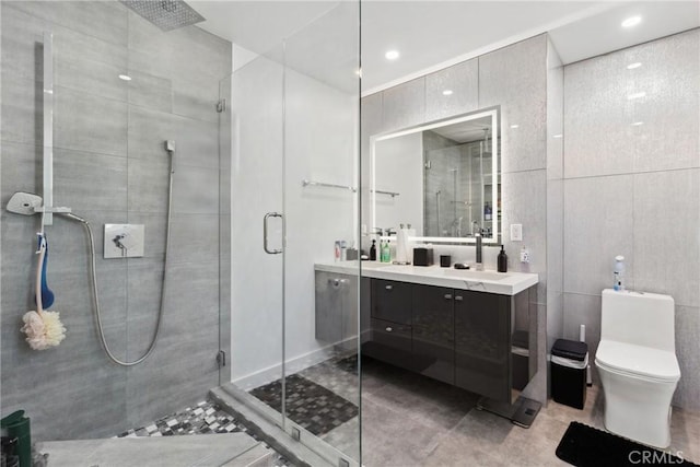 full bath featuring toilet, vanity, a shower stall, and tile walls