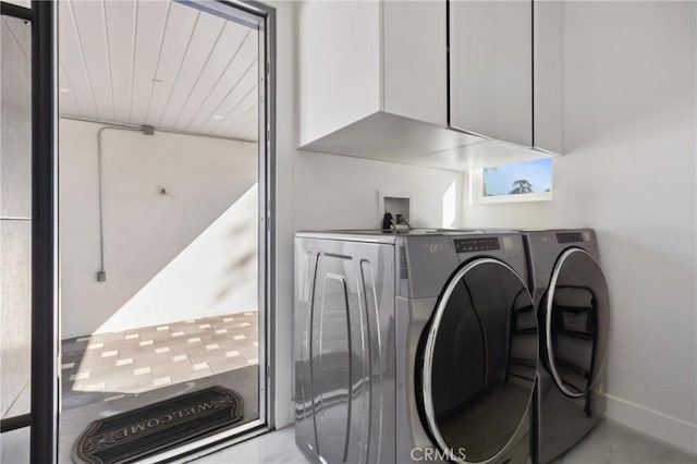 washroom with cabinet space, baseboards, and separate washer and dryer