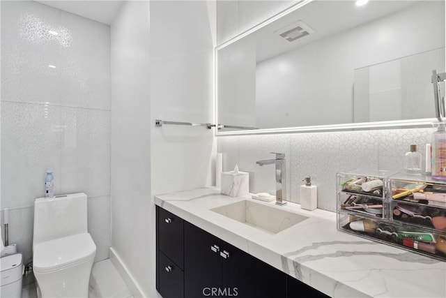 bathroom featuring toilet, visible vents, decorative backsplash, and vanity