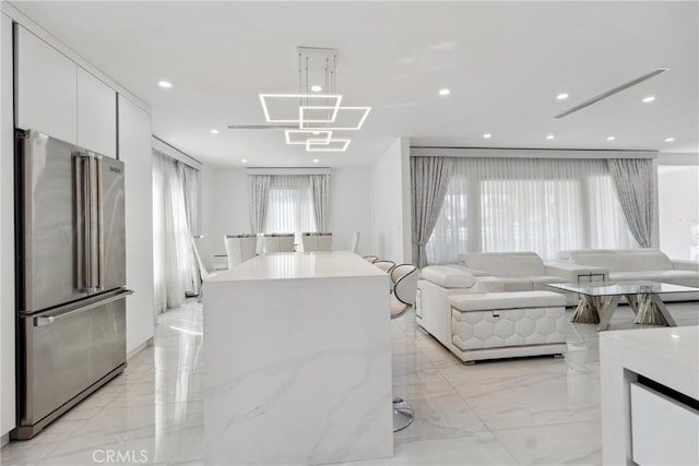 living room featuring a chandelier, marble finish floor, and recessed lighting