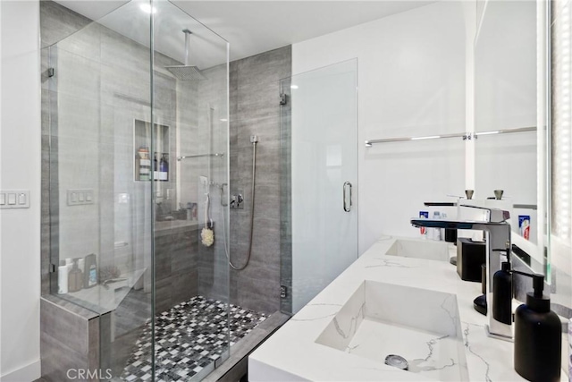 bathroom with a shower stall and double vanity