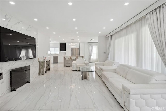 living room with marble finish floor, a high end fireplace, and recessed lighting