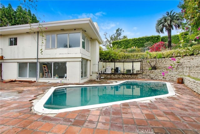 back of property featuring an outdoor pool and a patio