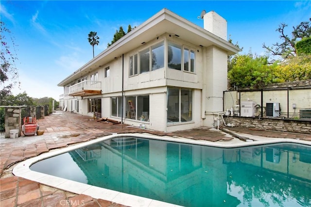 back of house featuring an outdoor pool, a patio, and a chimney