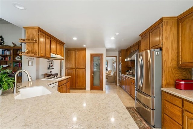 kitchen featuring brown cabinetry, white appliances, a sink, and under cabinet range hood