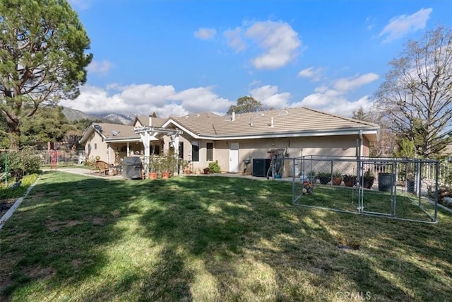 rear view of house with fence, a tiled roof, a lawn, stucco siding, and a patio area