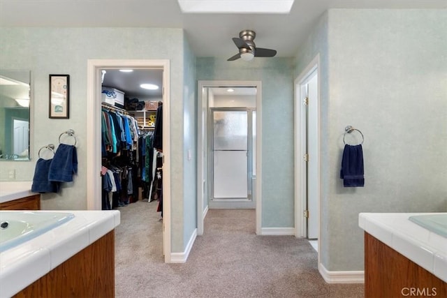 bathroom with carpet floors, a stall shower, ceiling fan, and two vanities