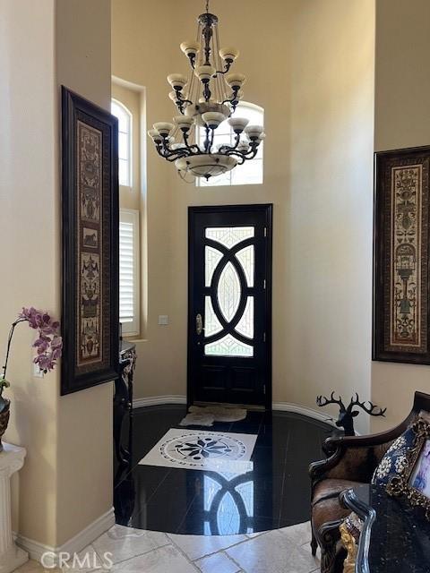 tiled foyer with a chandelier and baseboards