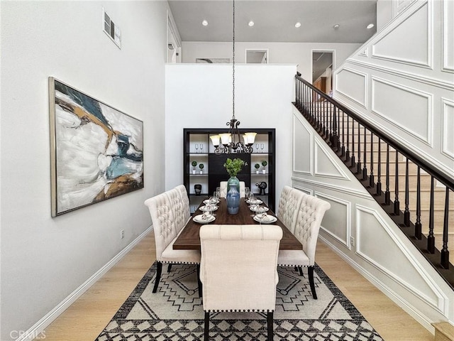 dining area with visible vents, baseboards, light wood-style flooring, stairway, and a chandelier