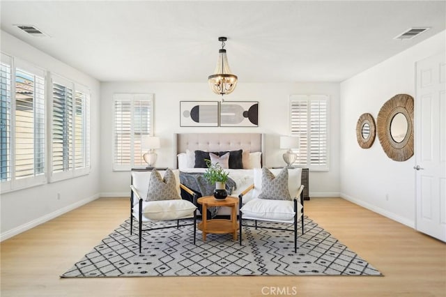 sitting room featuring a chandelier, light wood-type flooring, visible vents, and baseboards