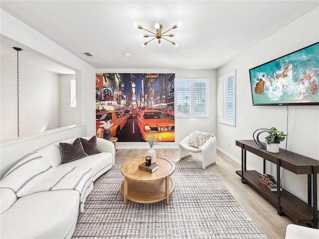 sitting room featuring baseboards, light wood-style flooring, visible vents, and a notable chandelier