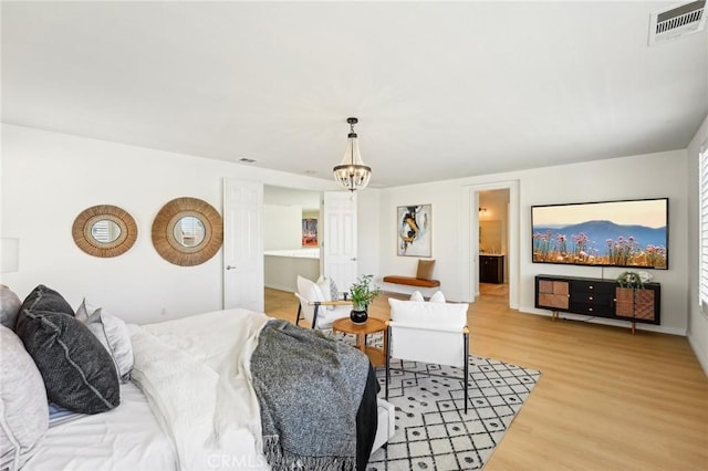 bedroom with visible vents, a chandelier, and wood finished floors