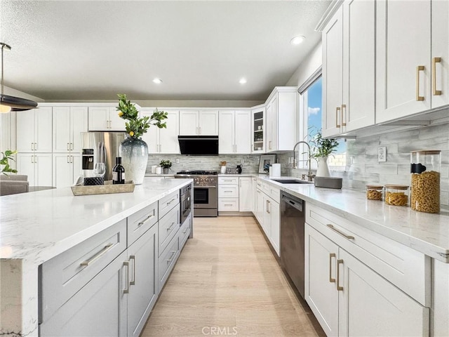 kitchen featuring appliances with stainless steel finishes, white cabinets, a sink, and glass insert cabinets