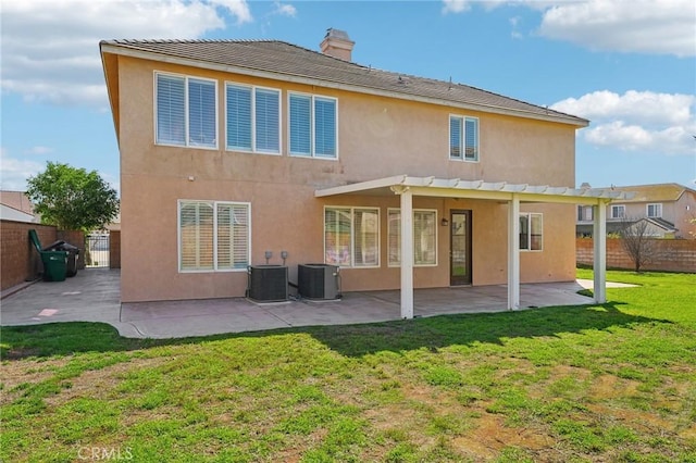 back of property with a yard, a chimney, a patio, stucco siding, and a fenced backyard