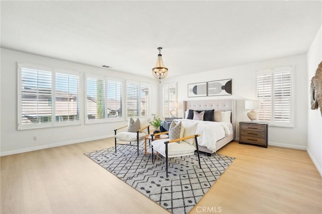 bedroom with light wood finished floors, baseboards, visible vents, and a notable chandelier