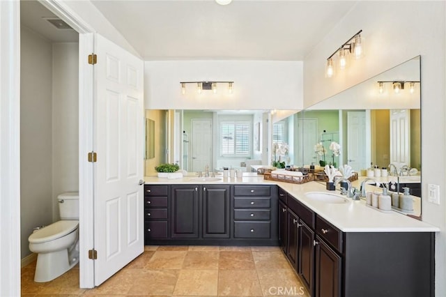 bathroom with double vanity, a sink, and toilet