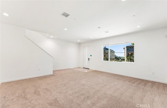 empty room featuring light colored carpet, visible vents, baseboards, and recessed lighting