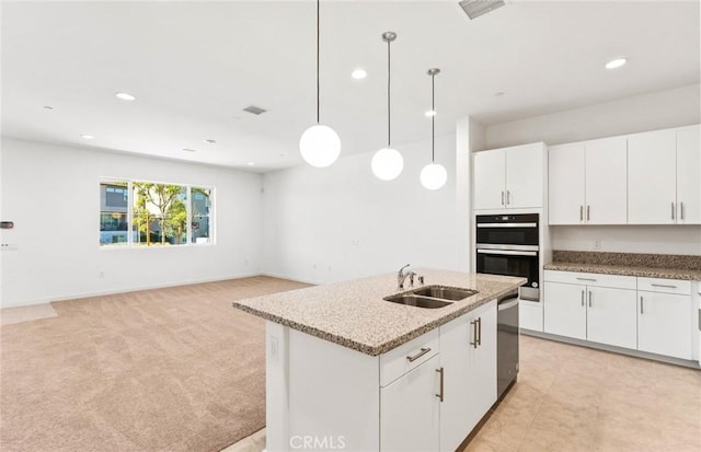 kitchen featuring appliances with stainless steel finishes, a kitchen island with sink, white cabinetry, pendant lighting, and a sink