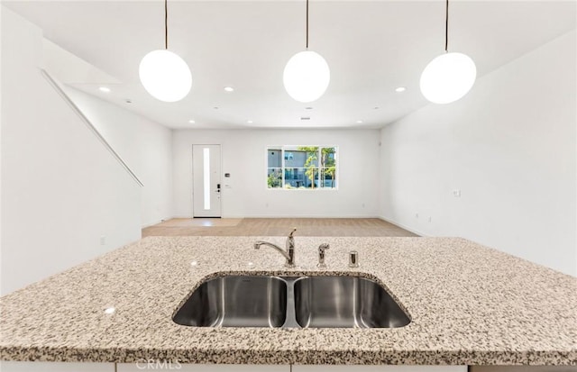 kitchen featuring open floor plan, hanging light fixtures, and a sink