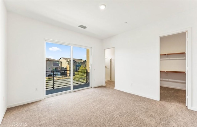 unfurnished bedroom with carpet floors, a closet, a spacious closet, access to outside, and baseboards