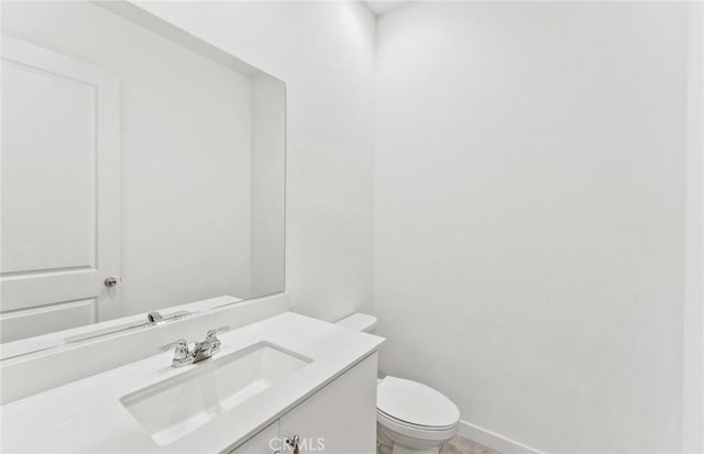 bathroom with baseboards, vanity, and toilet