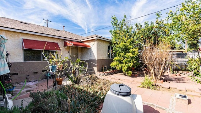 view of side of home with stucco siding, fence, and a patio