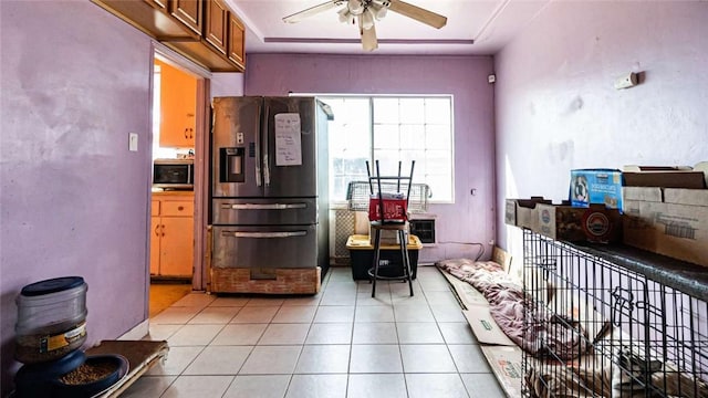 kitchen with light tile patterned floors, appliances with stainless steel finishes, brown cabinetry, and a ceiling fan