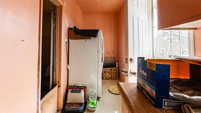 interior space featuring tile patterned floors and freestanding refrigerator