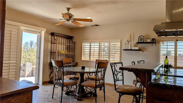 dining room with baseboards, visible vents, a ceiling fan, a textured ceiling, and light tile patterned flooring