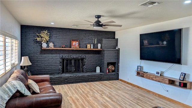 living area with a textured ceiling, a fireplace, visible vents, and wood finished floors