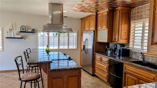 kitchen featuring black dishwasher, brown cabinets, a breakfast bar area, island range hood, and stainless steel fridge with ice dispenser