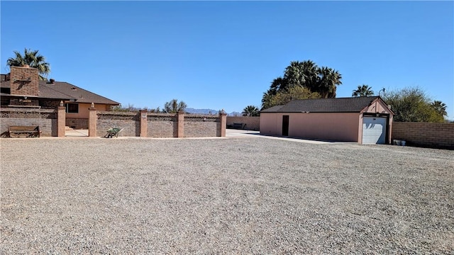 view of yard with an outbuilding, a detached garage, and fence