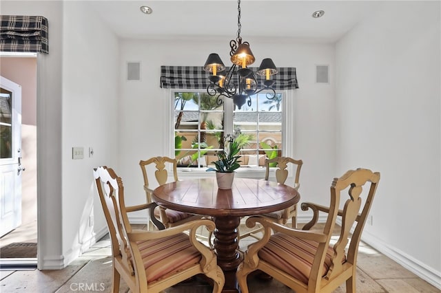 dining area featuring baseboards, stone tile floors, visible vents, and a notable chandelier