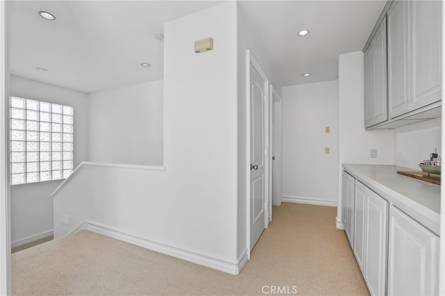 hall with baseboards, light colored carpet, and recessed lighting