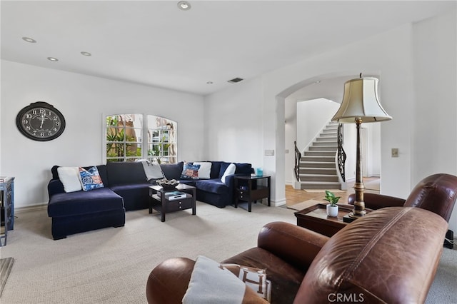 living area featuring visible vents, arched walkways, light colored carpet, stairway, and recessed lighting