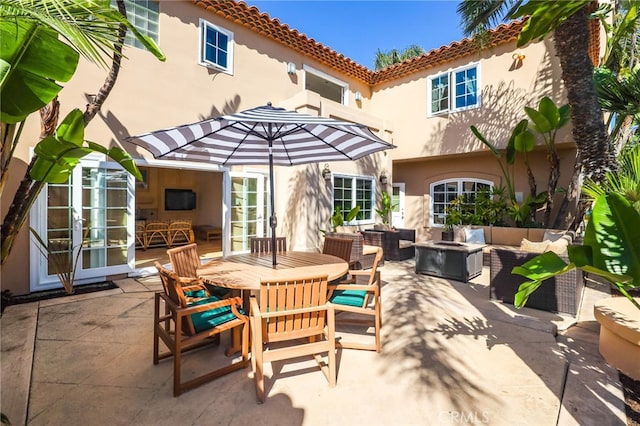 back of house featuring an outdoor living space with a fire pit, stucco siding, a patio, and french doors