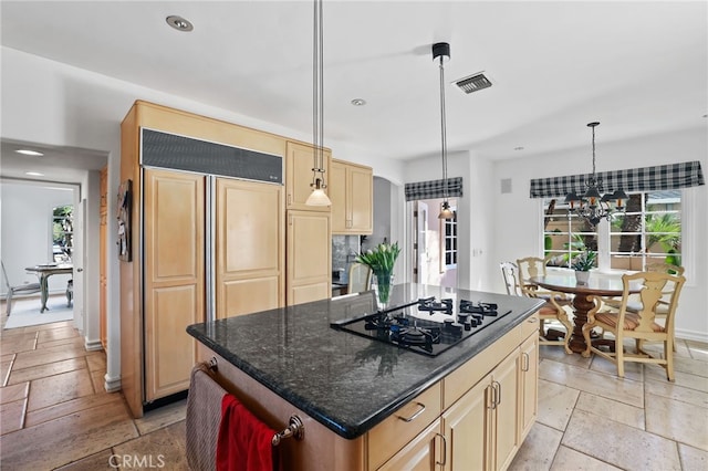 kitchen featuring black gas cooktop, a kitchen island, visible vents, dark stone counters, and pendant lighting