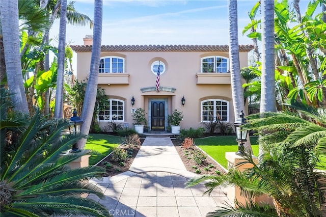 mediterranean / spanish home featuring a tile roof, a front yard, and stucco siding