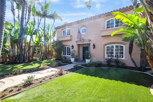 mediterranean / spanish-style home featuring a front lawn and stucco siding