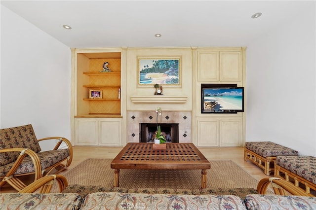 living room with built in features, recessed lighting, and a tiled fireplace