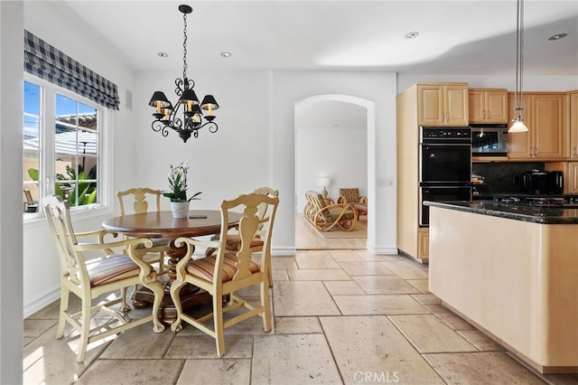 dining area featuring arched walkways, stone tile flooring, baseboards, and recessed lighting