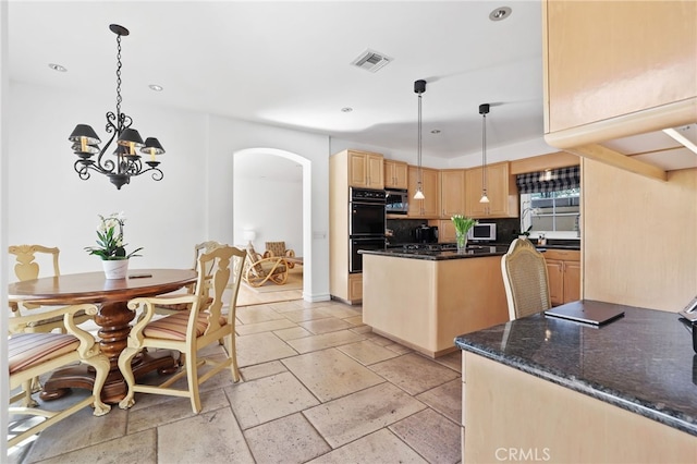 kitchen featuring arched walkways, stone tile floors, visible vents, hanging light fixtures, and light brown cabinets